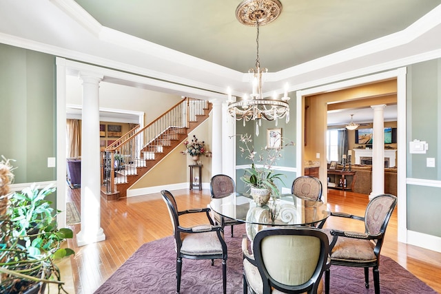 dining room featuring decorative columns, ornamental molding, hardwood / wood-style floors, and a tray ceiling