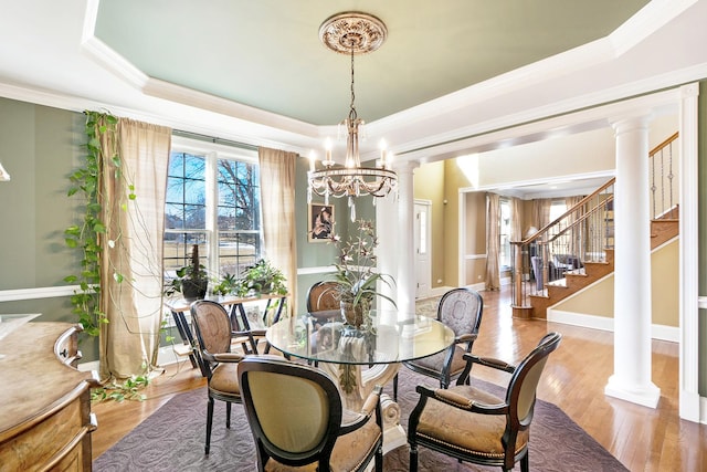 dining room featuring decorative columns, crown molding, hardwood / wood-style floors, and a tray ceiling