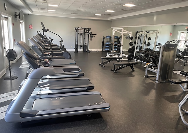 workout area featuring a paneled ceiling and baseboards