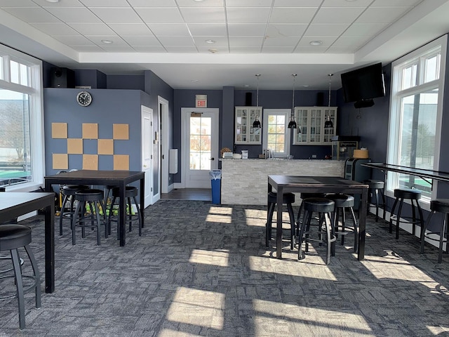 carpeted dining space featuring a drop ceiling and baseboards