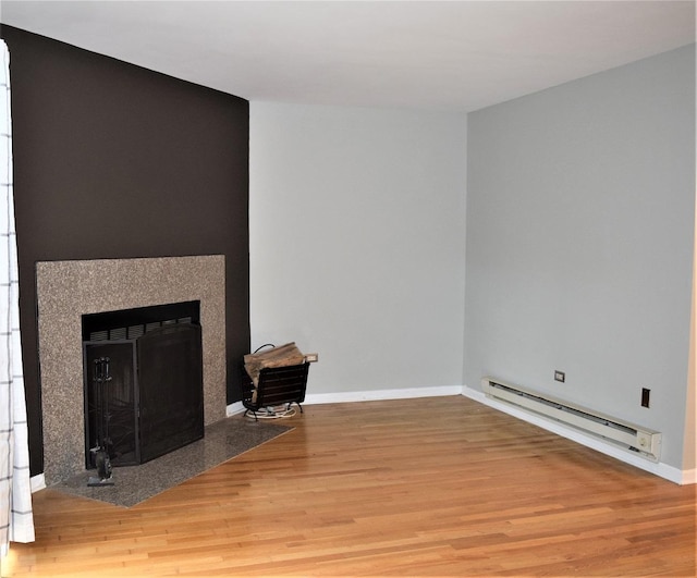 unfurnished living room with baseboard heating and hardwood / wood-style floors