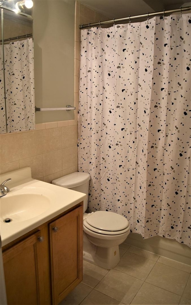 bathroom featuring backsplash, tile patterned floors, vanity, tile walls, and toilet