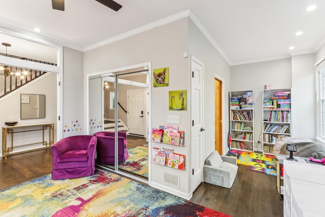 rec room with crown molding, dark wood-type flooring, and ceiling fan