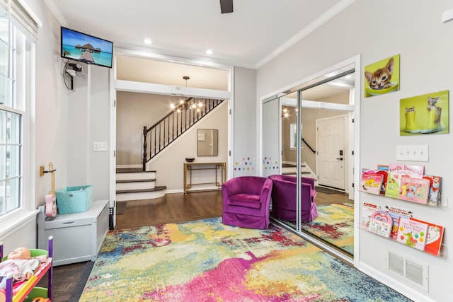 rec room with crown molding, dark hardwood / wood-style flooring, and an inviting chandelier