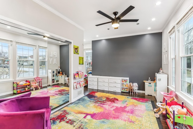 rec room with crown molding, plenty of natural light, and dark hardwood / wood-style flooring