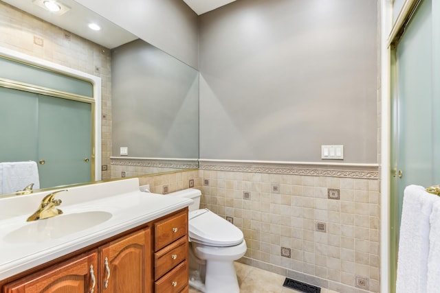 bathroom with vanity, tile patterned floors, tile walls, and toilet