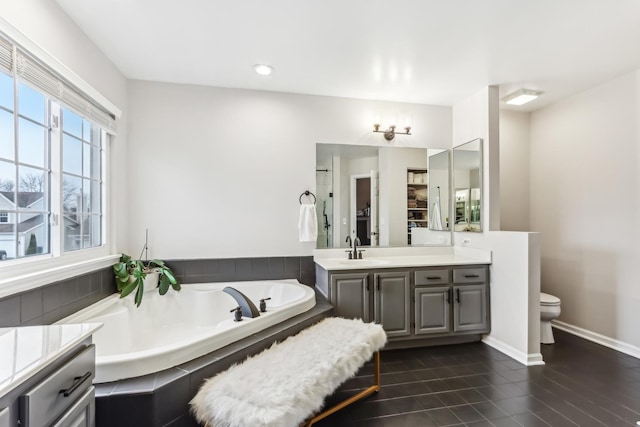 bathroom with a tub to relax in, toilet, and vanity