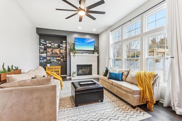 living room with ceiling fan, a fireplace, and light hardwood / wood-style floors