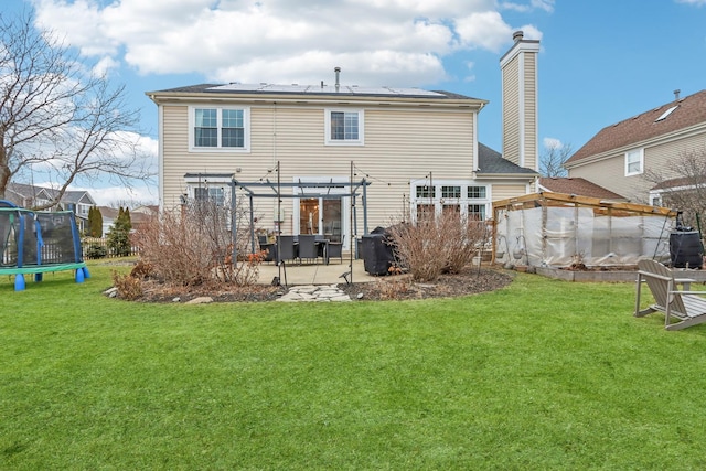 back of house featuring a trampoline, a yard, a pergola, and a patio area