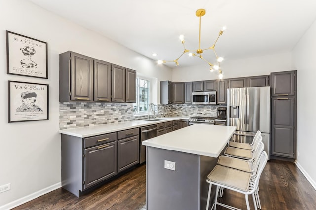 kitchen with sink, appliances with stainless steel finishes, hanging light fixtures, tasteful backsplash, and a kitchen island