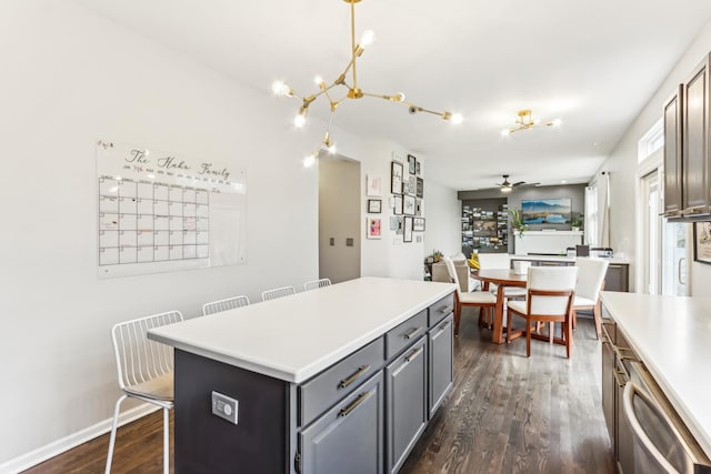 kitchen with dark hardwood / wood-style floors, a breakfast bar, gray cabinetry, a center island, and ceiling fan