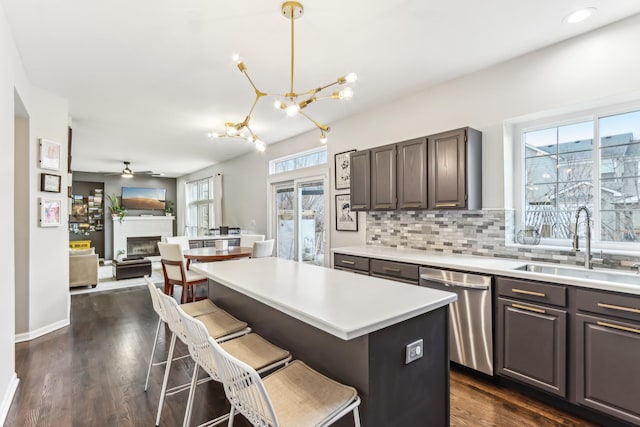 kitchen with sink, decorative light fixtures, a center island, a kitchen breakfast bar, and dishwasher