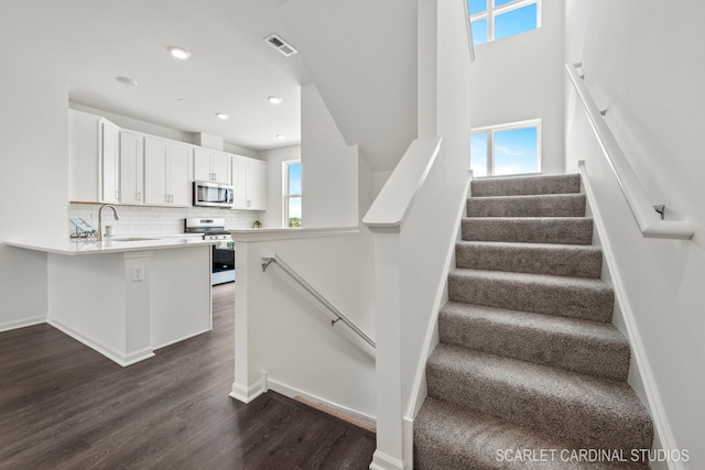 stairs with recessed lighting, visible vents, and wood finished floors