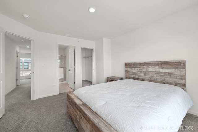 bedroom featuring a walk in closet, recessed lighting, ensuite bathroom, carpet flooring, and baseboards