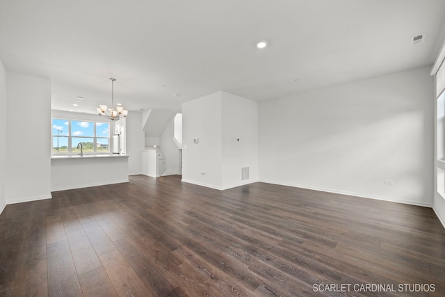 unfurnished living room with baseboards, visible vents, dark wood finished floors, and a notable chandelier