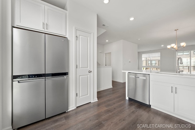 kitchen with sink, dark hardwood / wood-style flooring, a notable chandelier, white cabinets, and appliances with stainless steel finishes