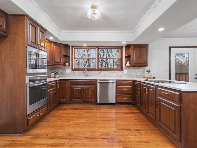 kitchen featuring sink, stainless steel appliances, a raised ceiling, backsplash, and crown molding