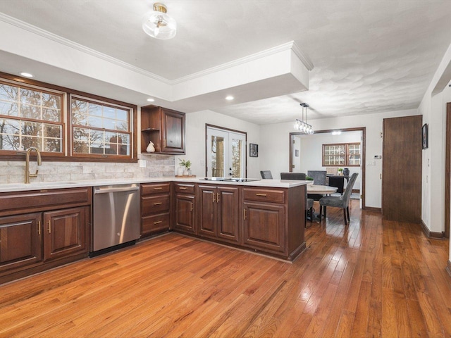 kitchen with kitchen peninsula, tasteful backsplash, stainless steel dishwasher, crown molding, and sink