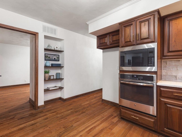 kitchen with decorative backsplash, built in features, dark hardwood / wood-style floors, and appliances with stainless steel finishes