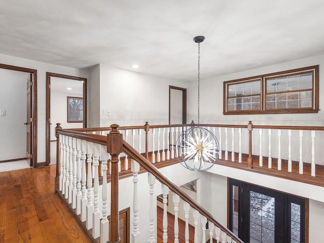 corridor featuring a healthy amount of sunlight, dark hardwood / wood-style flooring, and a notable chandelier