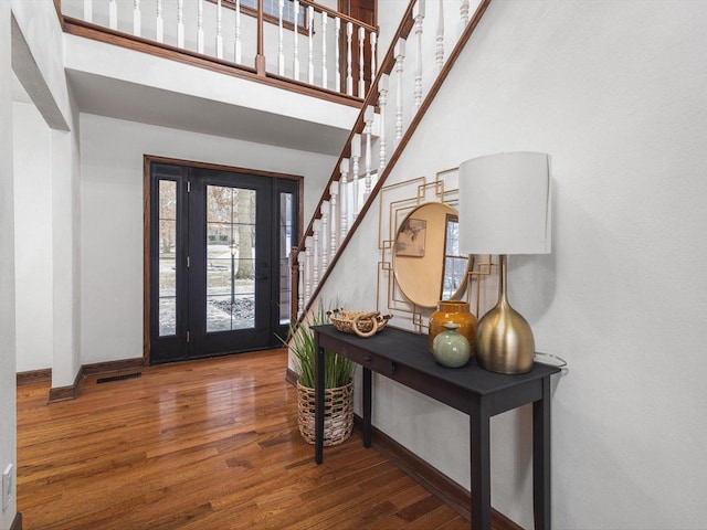 entryway featuring a towering ceiling and dark wood-type flooring