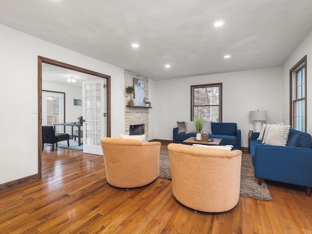 living room featuring a stone fireplace, french doors, and wood-type flooring