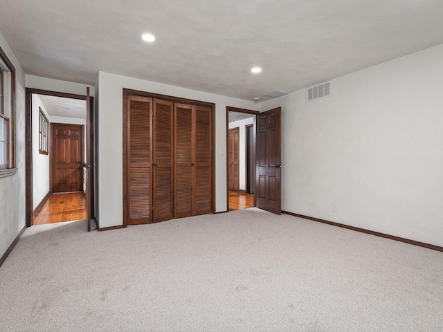 unfurnished bedroom with light carpet and a closet