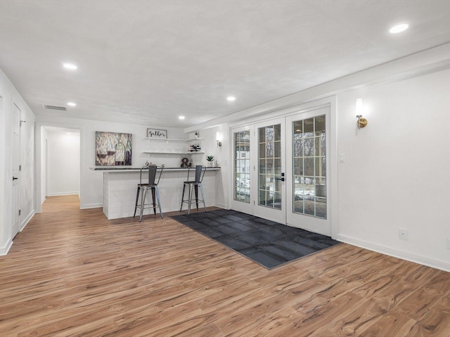 interior space with kitchen peninsula, a kitchen breakfast bar, hardwood / wood-style flooring, and french doors