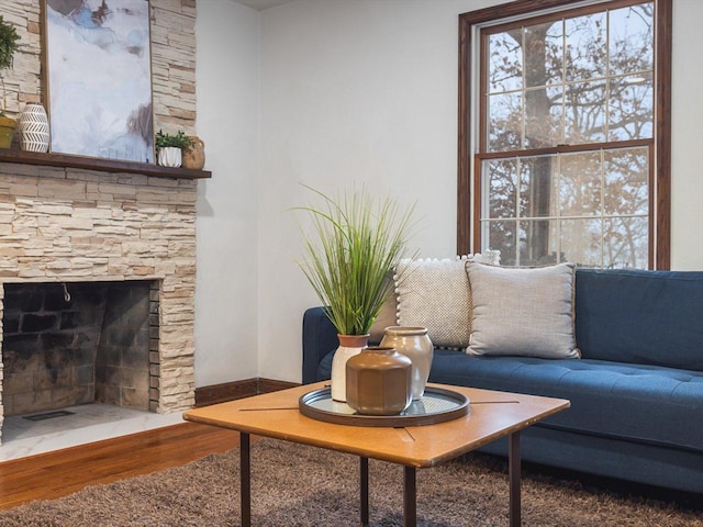 living room with a stone fireplace and hardwood / wood-style floors