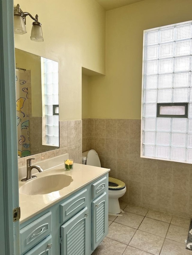 bathroom with tile patterned floors, vanity, toilet, and tile walls