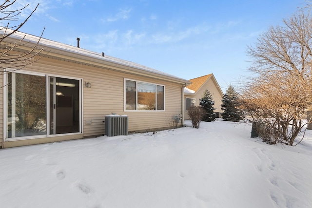 snow covered rear of property featuring central air condition unit