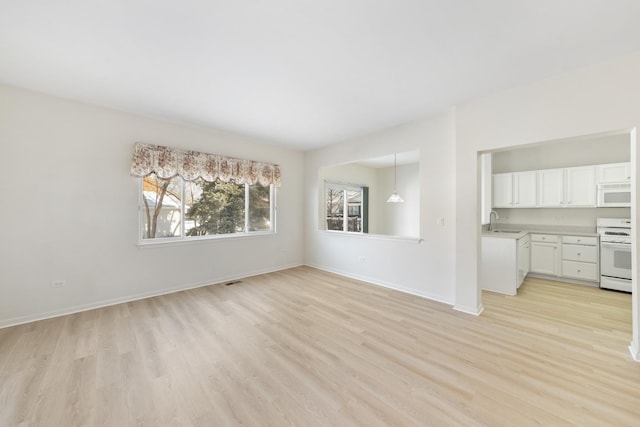 unfurnished living room featuring sink and light hardwood / wood-style floors