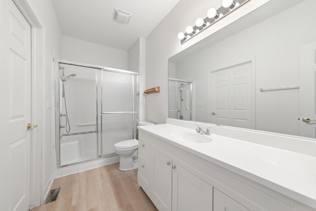 bathroom featuring toilet, an enclosed shower, wood-type flooring, and vanity