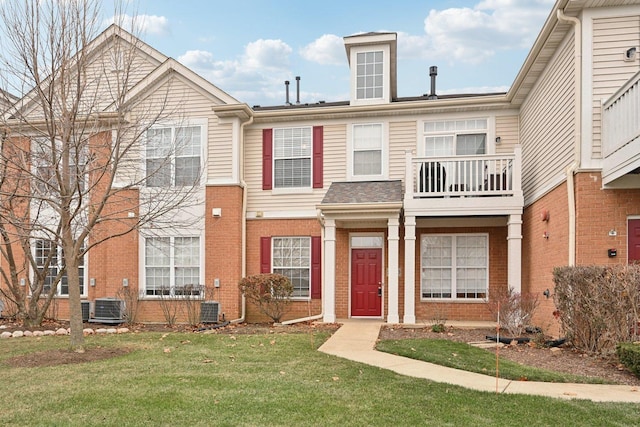 view of property featuring a front yard, a balcony, and central AC unit