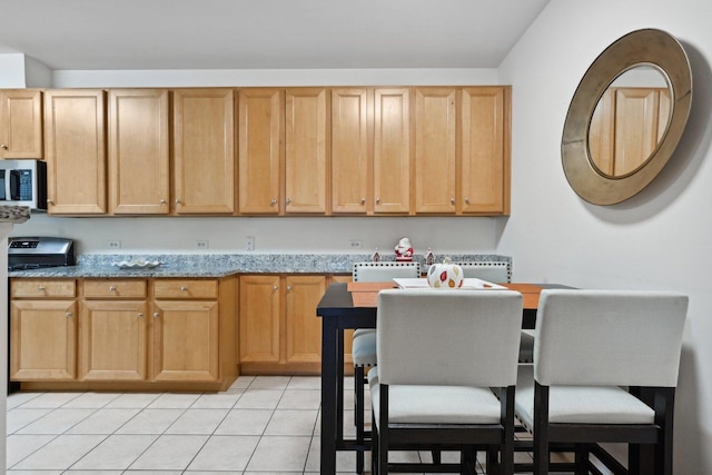 kitchen featuring light tile patterned floors and light stone counters