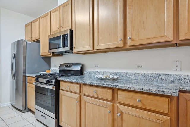 kitchen featuring light brown cabinets, light stone countertops, light tile patterned floors, and appliances with stainless steel finishes