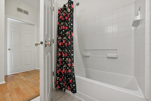 bathroom with shower / bathtub combination with curtain and wood-type flooring