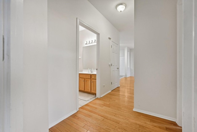 corridor with light wood-type flooring and sink