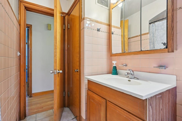 bathroom with tile walls, tile patterned flooring, and vanity