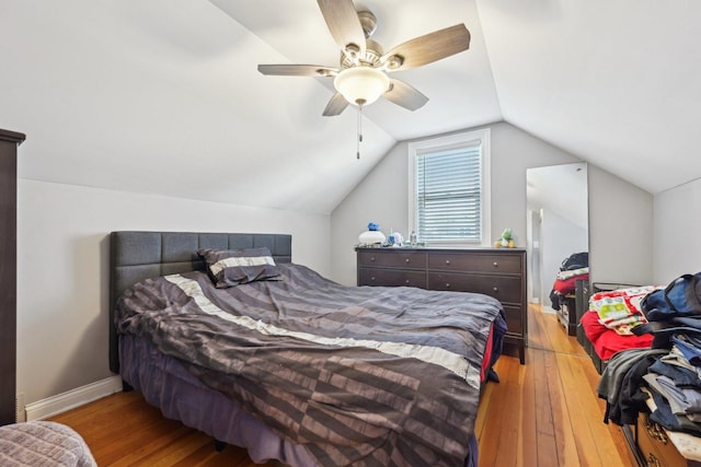 bedroom with ceiling fan, lofted ceiling, and wood-type flooring