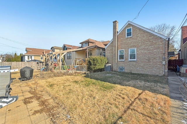 rear view of house featuring central air condition unit and a yard