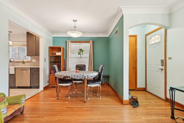 dining area with crown molding and light wood-type flooring