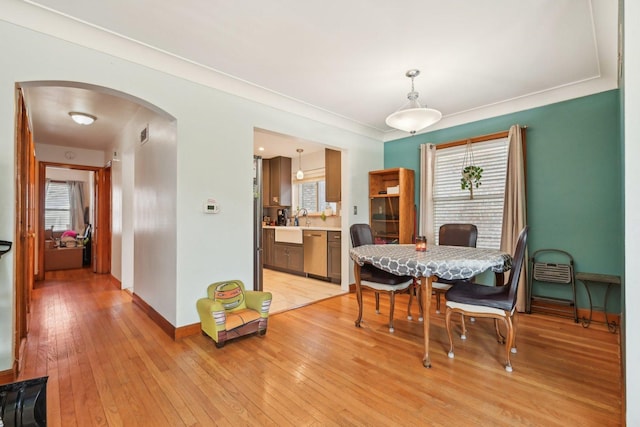 dining space featuring sink, crown molding, and light wood-type flooring