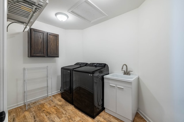 laundry area with sink, independent washer and dryer, light hardwood / wood-style floors, and cabinets