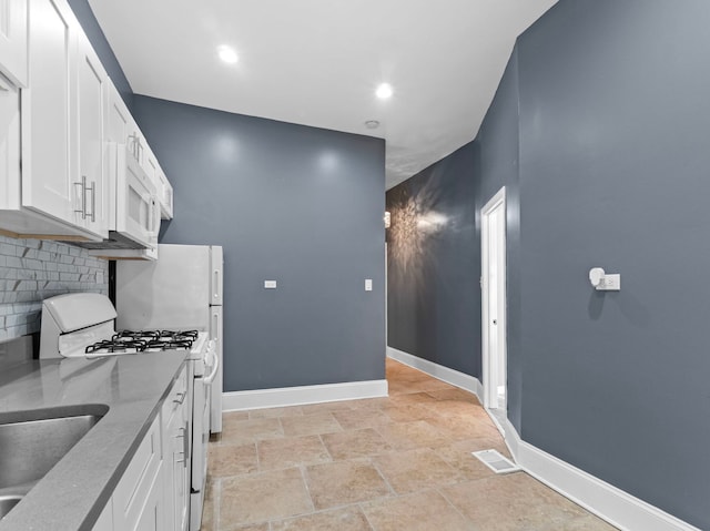 kitchen featuring white cabinets, tasteful backsplash, gas range gas stove, and light stone counters