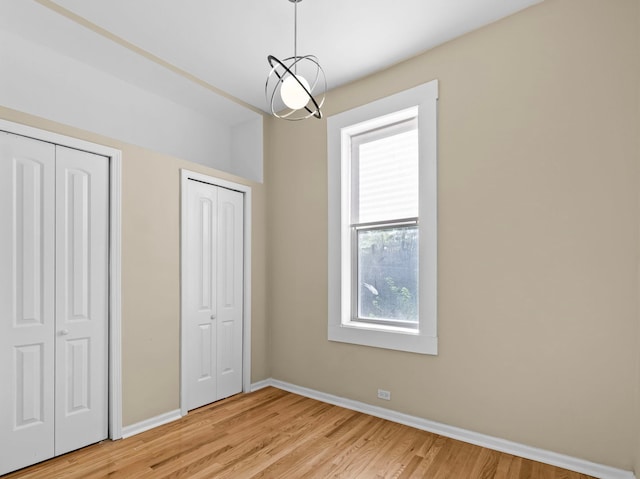 unfurnished bedroom with multiple closets and light hardwood / wood-style flooring