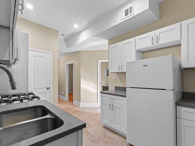 kitchen featuring white refrigerator, white cabinetry, and sink