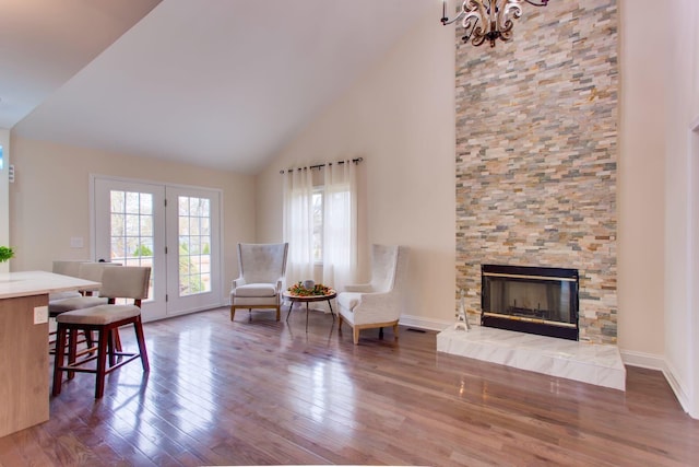 living area featuring hardwood / wood-style flooring, high vaulted ceiling, a notable chandelier, and a fireplace