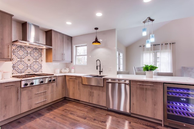 kitchen with wine cooler, appliances with stainless steel finishes, sink, wall chimney range hood, and decorative light fixtures