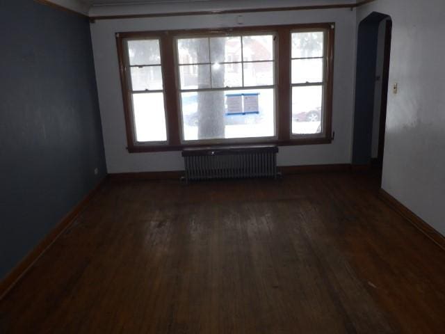 empty room featuring radiator and dark wood-type flooring